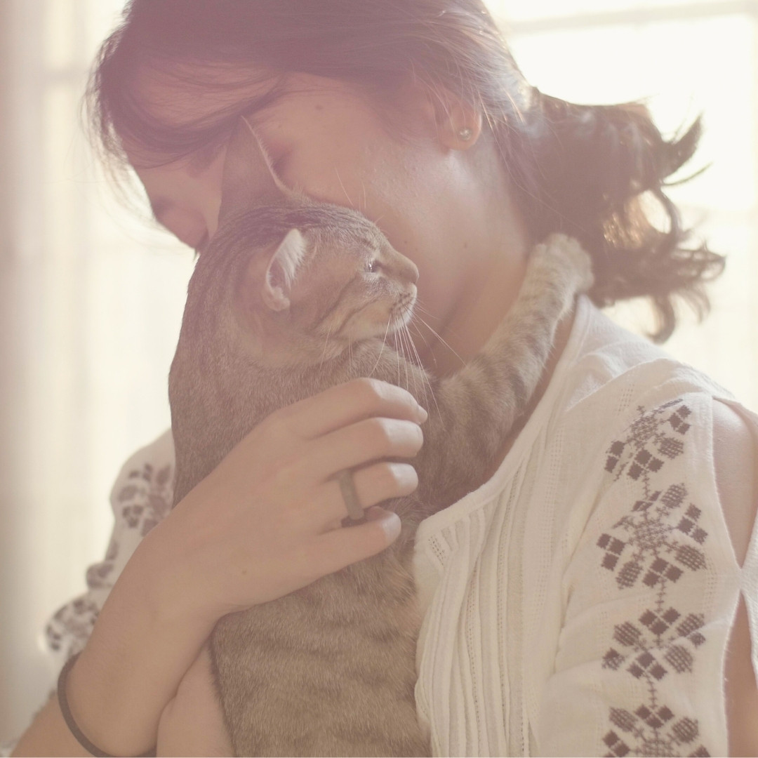 a woman embraces a cat lovingly in a cozy room
