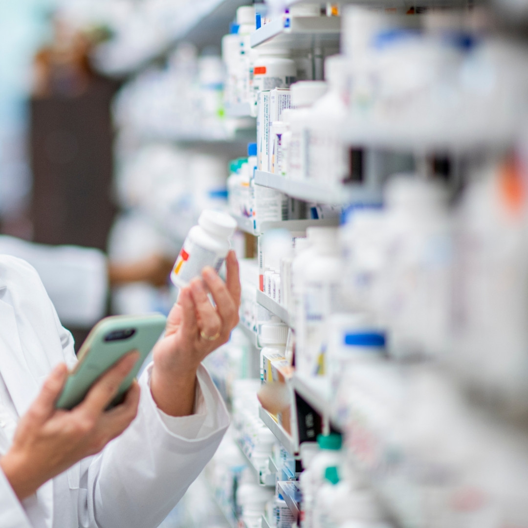 pharmacy a woman in a white lab coat looks intently at a tablet